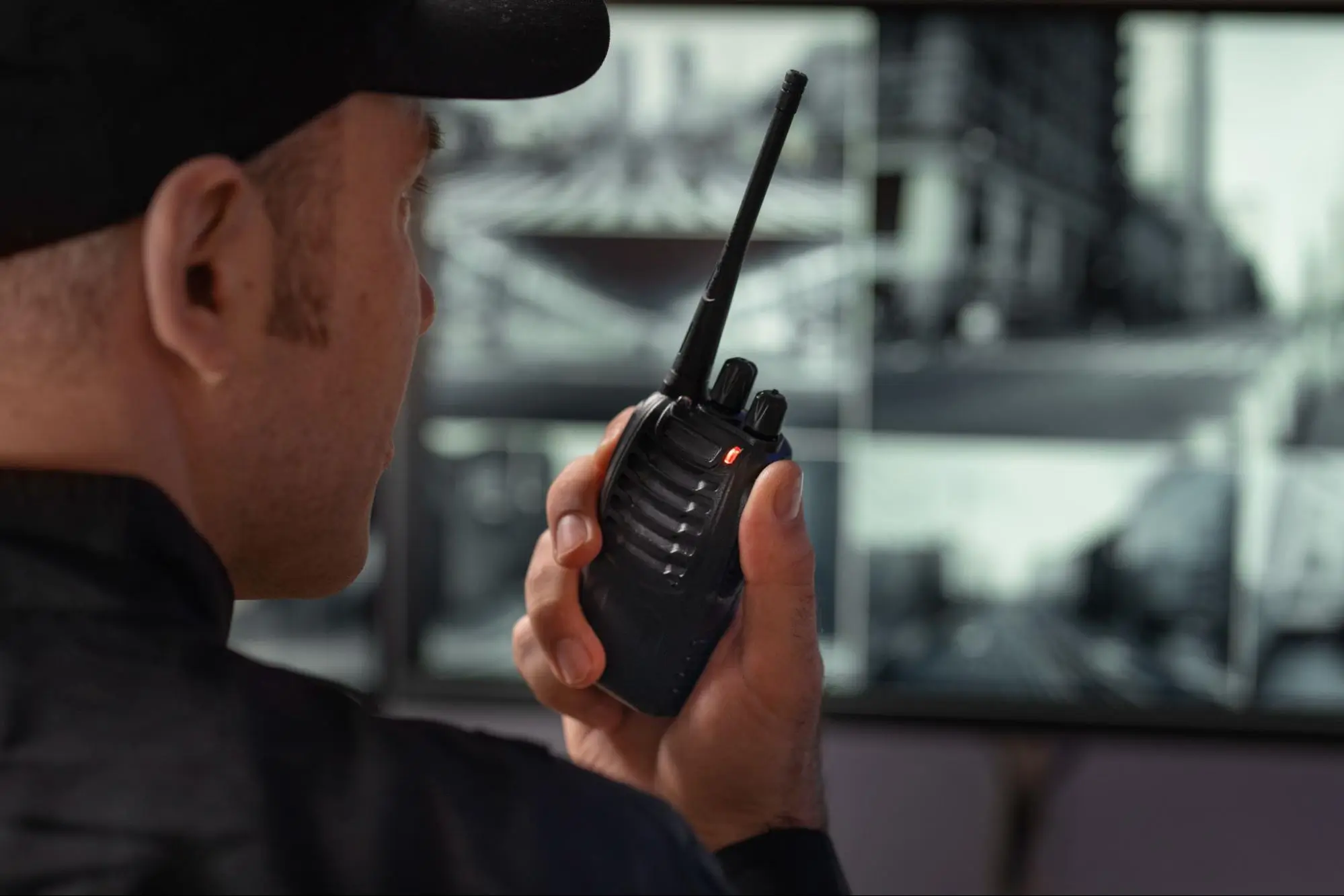 Security Guard Radio Communication & Surveillance Monitoring | American Security Force (ASF) Professional security guard using two-way radio while monitoring live surveillance cameras in a security control room, providing rapid response services by American Security Force.